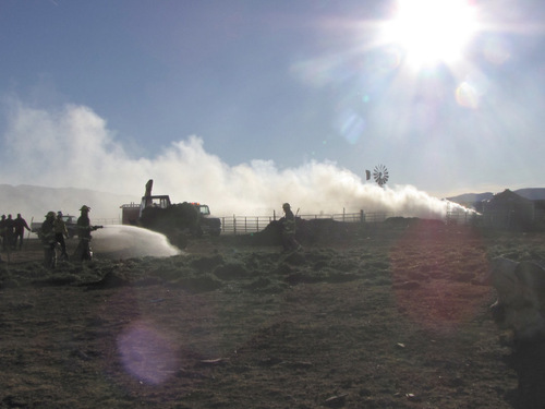 Firefighters put out burning hay bales in Iron County Sunday brought outside febced storage area by a tractor. Mark Havnes/The Salt lake Tribune